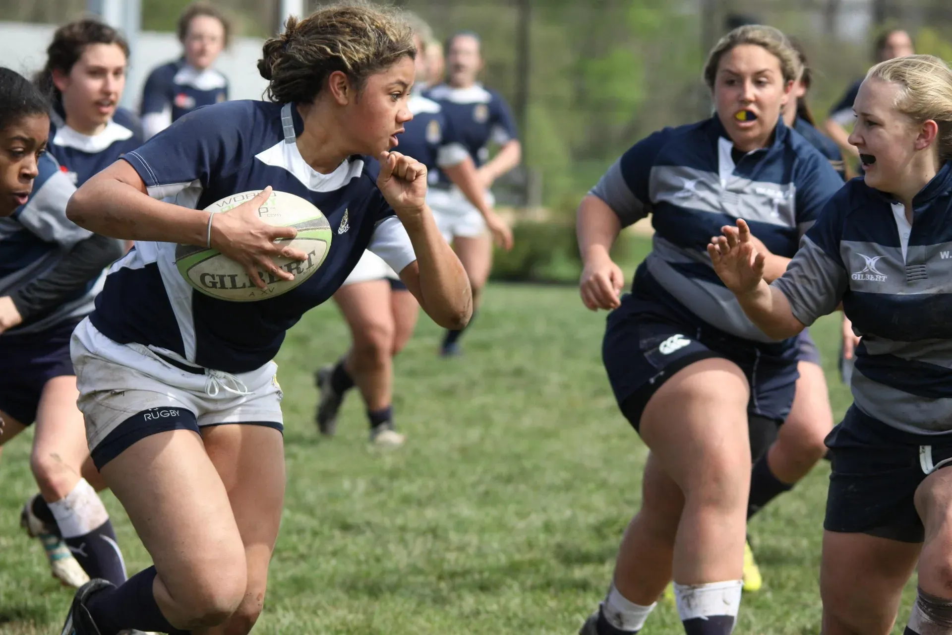 A women's rugby player carrying the ball into space during a match.