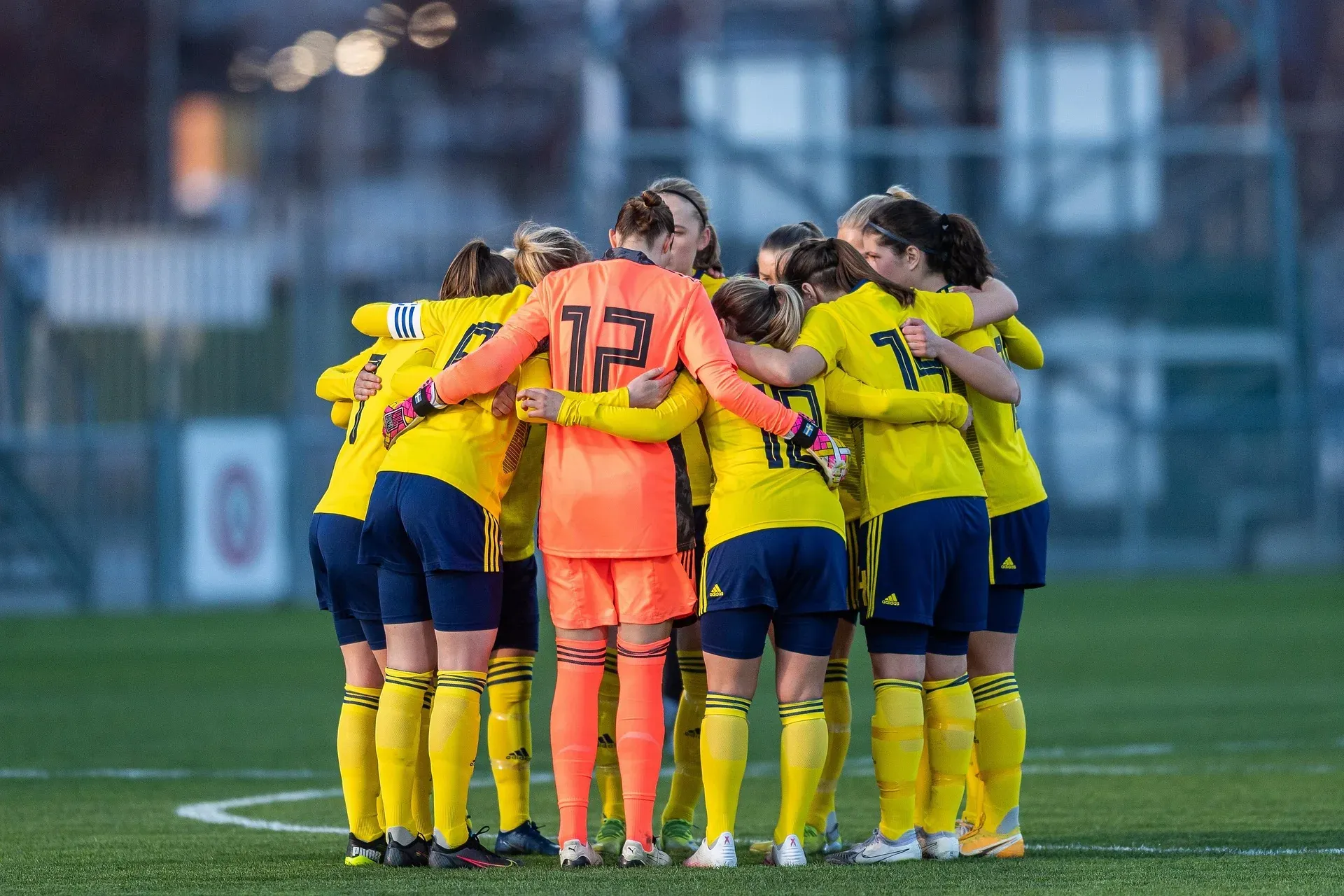 A women's football team in a close huddle before a match.
