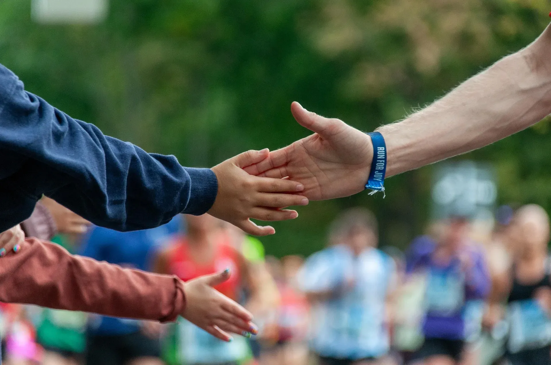 A runner reaching out to high-five children's outstretched hands at the roadside.