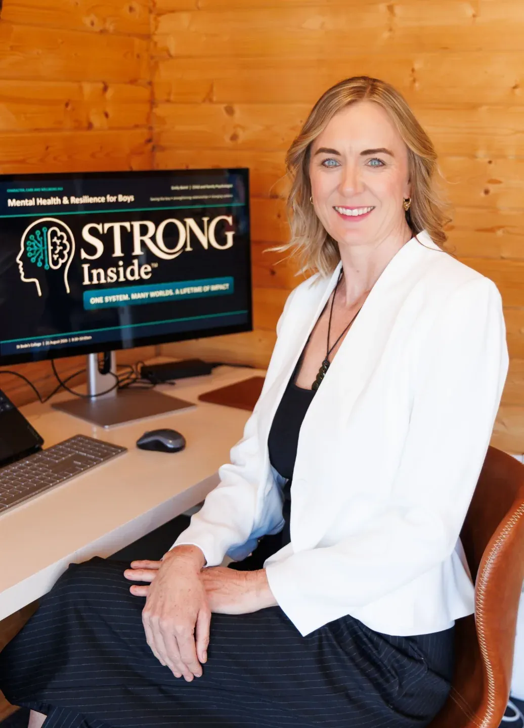 Emily Baird at her desk with the STRONG Inside logo on her screen.