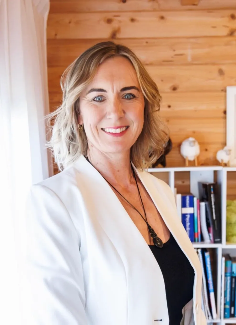 Emily Baird, Consultant Psychologist, smiling beside her bookshelf.