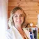 Emily Baird, Consultant Psychologist, smiling beside her bookshelf.