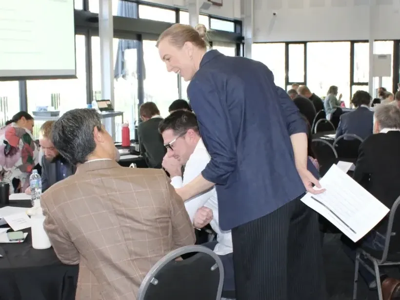 Emily Baird talking with staff at their table during a workshop.
