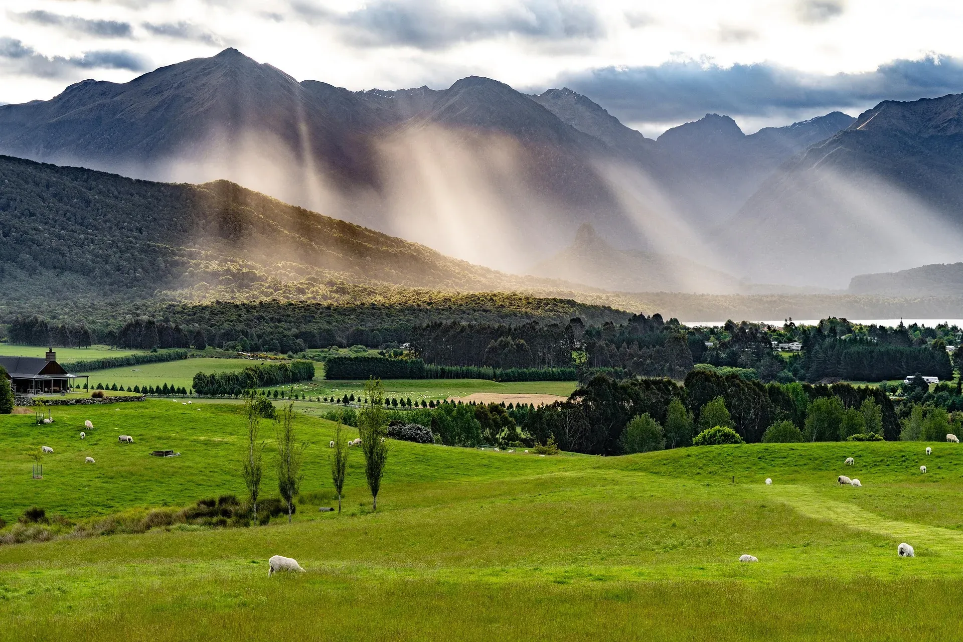 Light breaking through cloud over green farmland and mountains.