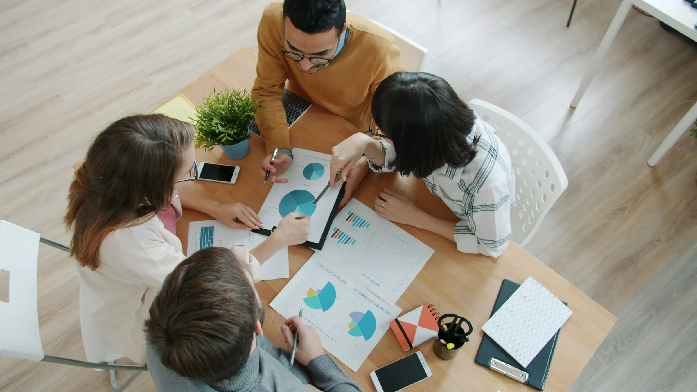 A team working together around a table covered in notes and charts, seen from above.